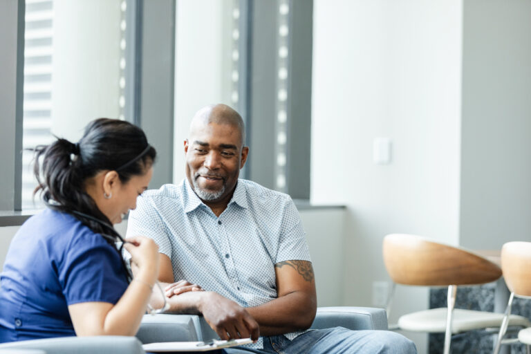 The young adult female nurse meets with the male patient in the medical clinic lobby to interview him before his procedure.