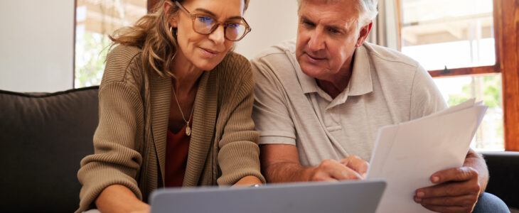 Retirement couple budget, finance and investment planning, loan and paper bills with laptop technology in home. Mature people money, cash savings or legal insurance document report on online bank