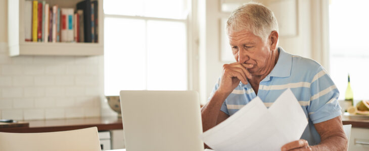 Shot of a senior man looking stressed while doing the household finances on a laptop in his kitchen