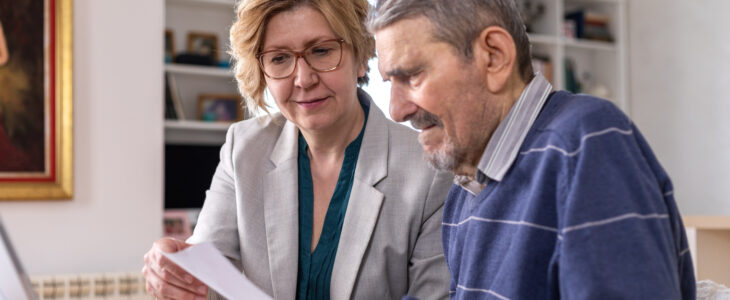 Mature woman helping senior man, 91 years old, with paperwork. He signing documents