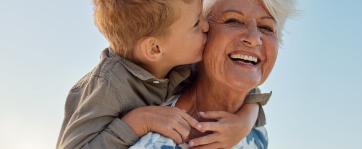 Kiss, child and grandmother in a park with love, care and freedom for happiness in retirement. Senior, smile and portrait of a woman with hug from a kid and kissing in nature or park with piggyback