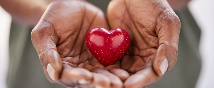 Close up of woman hands holding a small red heart. Small heart in the hands of a african woman. Solidarity, charity and responsibility concept.
