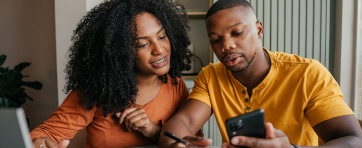 A couple looking at a phone screen while filing paperwork