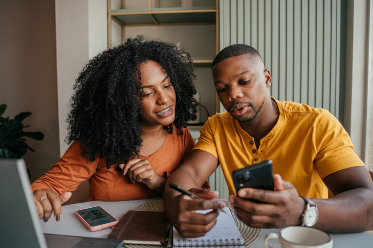 A couple looking at a phone screen while filing paperwork