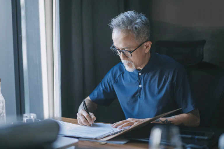 Asian chinese senior man signing legal documents in his room