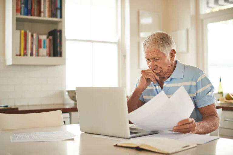 Shot of a senior man looking stressed while doing the household finances on a laptop in his kitchen