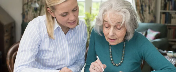 Woman Helping Senior Neighbor With Paperwork