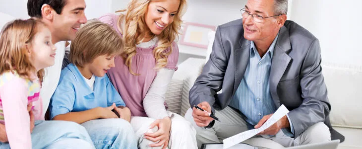 Adults with kids sitting in the living room and talking to the Insurance Agent.